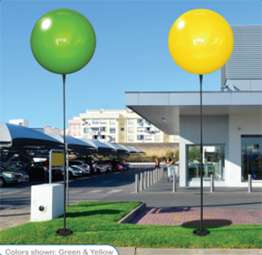 Green and yellow balloons outside modern building.